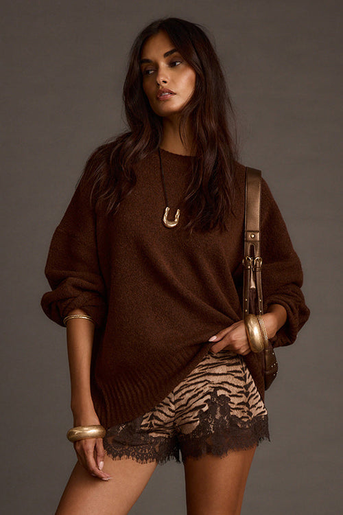 Woman wearing a brown oversized sweater with lace-trimmed shorts and a gold shoulder bag