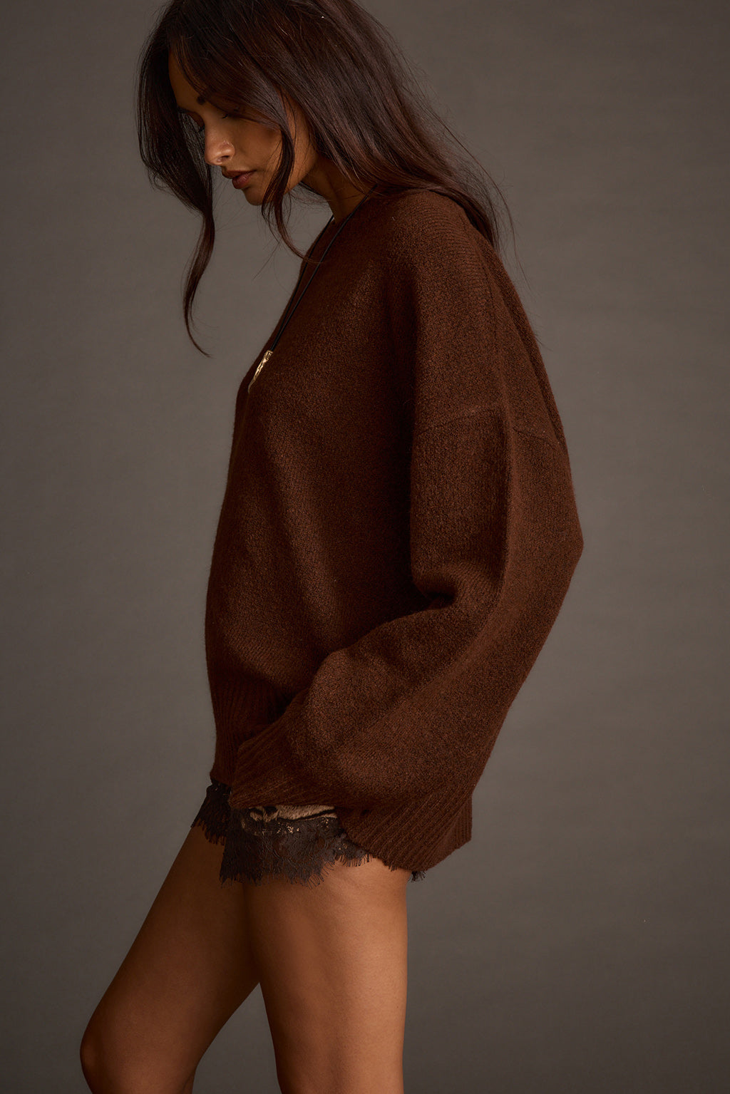 Side profile silhouette of a brown oversized sweater with lace-trim shorts underneath